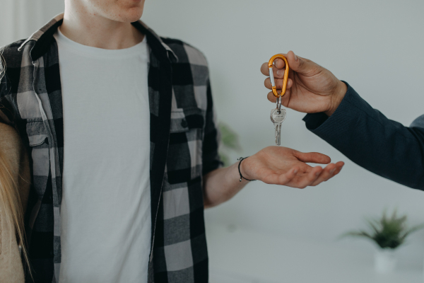 A happy young couple buying their new home and receiving keys from real estate agent