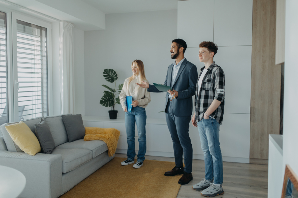 A happy young couple buying their new home and meeting real estate agent in apartment.