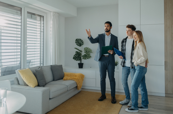 A happy young couple buying their new home and meeting real estate agent in apartment.