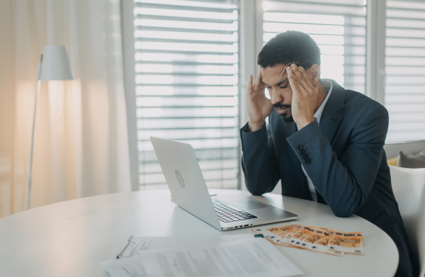 A depressed businessman man counting euro money working on computer at office desk, inflation concept.