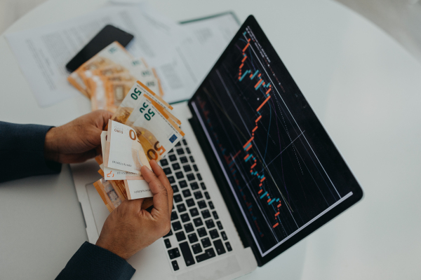 A businessman man counting euro money working on computer at office desk, inflation concept.