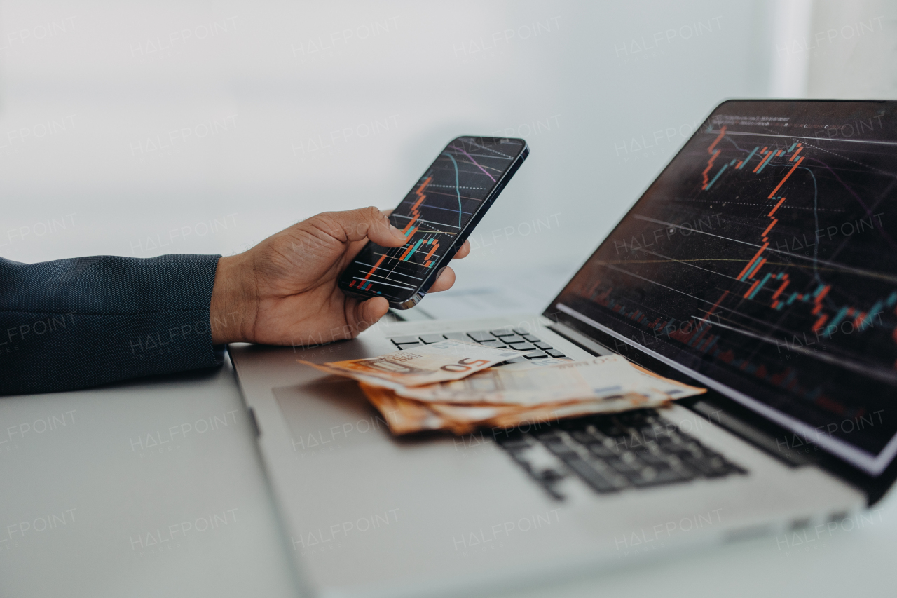 A businessman man counting euro money working on computer and smartphone at office desk, inflation concept.