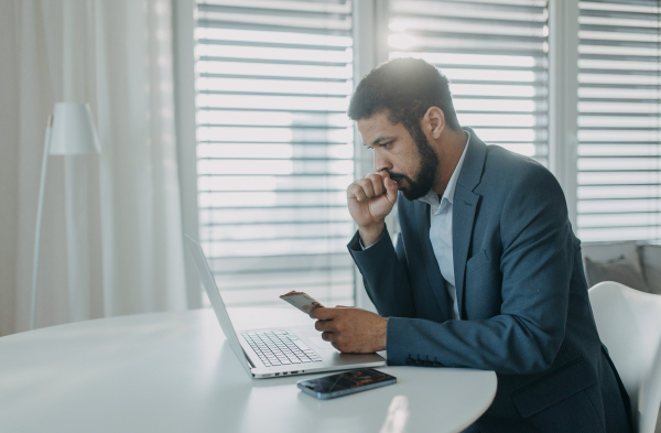 A depressed businessman man counting euro money working on computer at office desk, inflation concept.