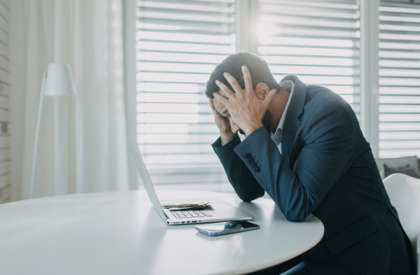 A depressed businessman man counting euro money working on computer at office desk, inflation concept.