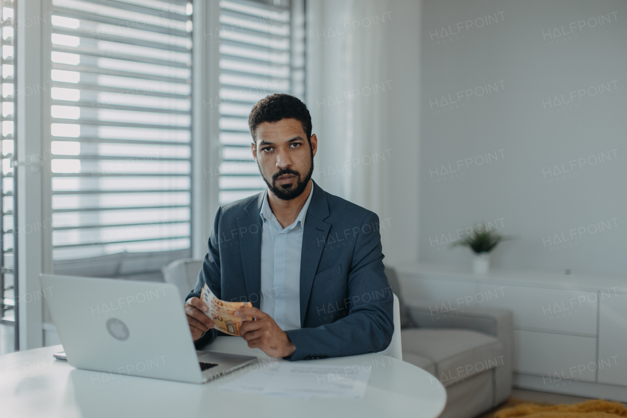 A depressed businessman man counting euro money working on computer at office desk, inflation concept.