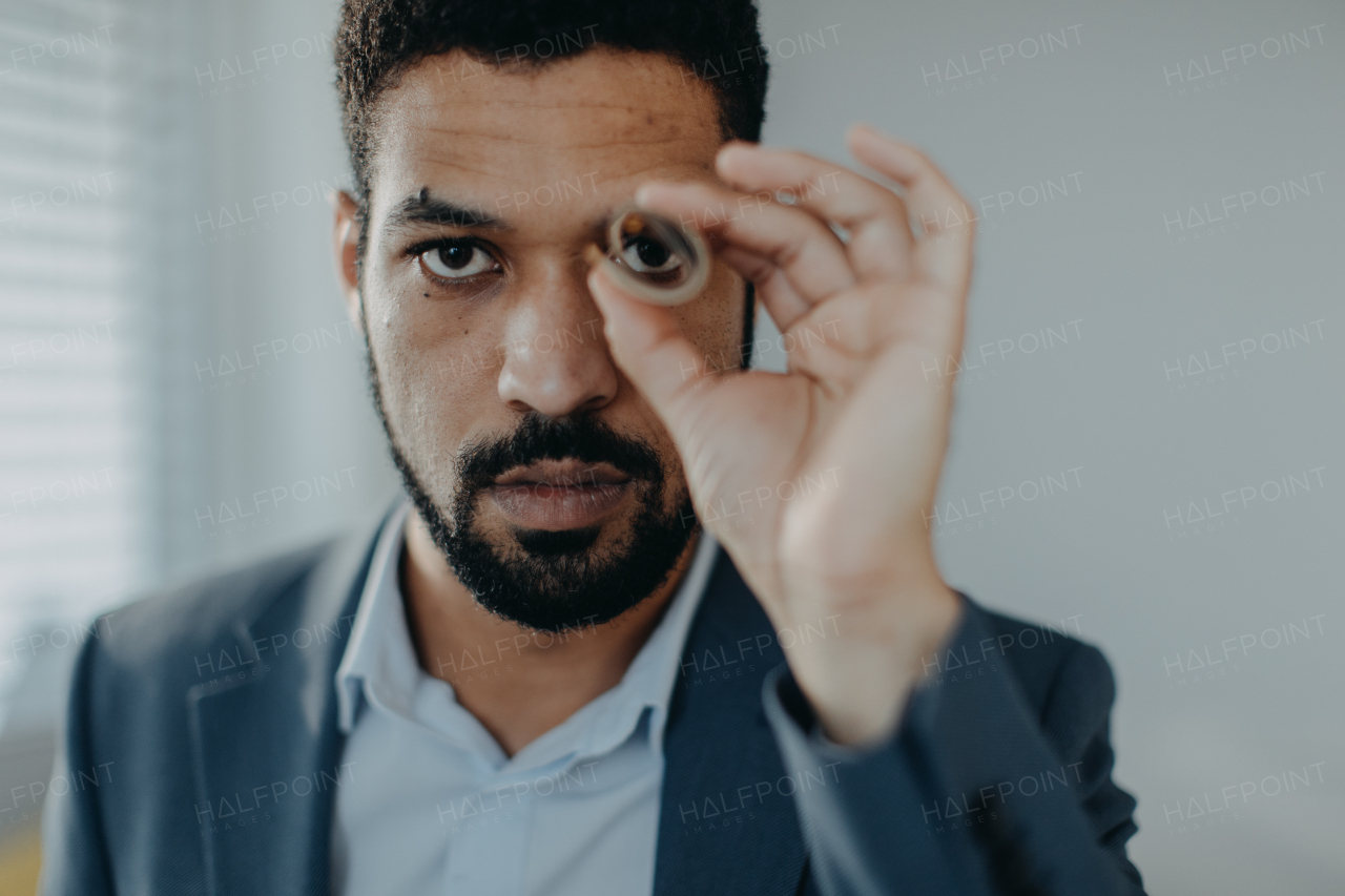 A depressed businessman man looking through a tube of money, inflation concept.