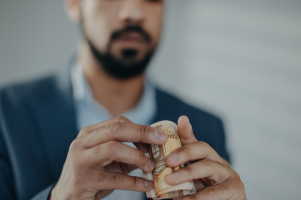 A depressed businessman man looking through a tube of money, inflation concept.