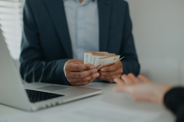 A businessman giving money to his partner while making contract - bribery and corruption concepts