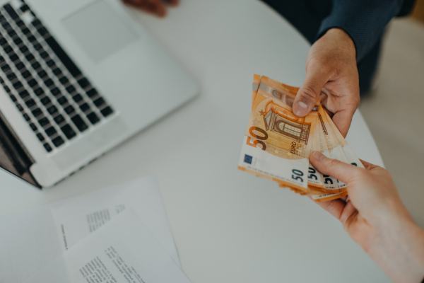 A businessman giving money to his partner while making contract - bribery and corruption concepts