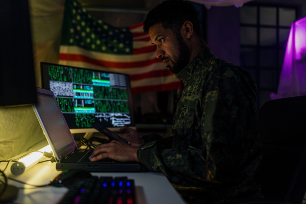 An American hacker in military unifrorm on dark web, cyberwar concept.