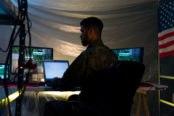 An American hacker in military unifrorm on dark web, cyberwar concept.