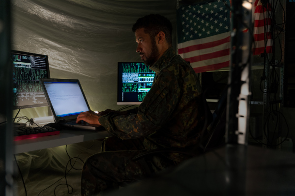 An American hacker in military unifrorm on dark web, cyberwar concept.