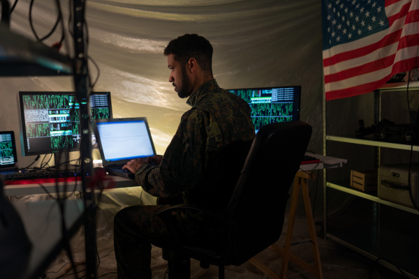 An American hacker in military unifrorm on dark web, cyberwar concept.