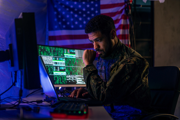 An American hacker in military unifrorm on dark web, cyberwar concept.