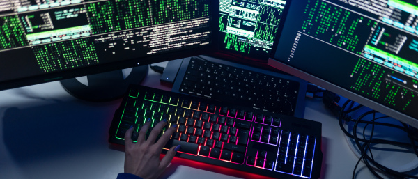 Close-up of a woman hacker hands at keyboard computer in the dark room at night, cyberwar concept. Side view.