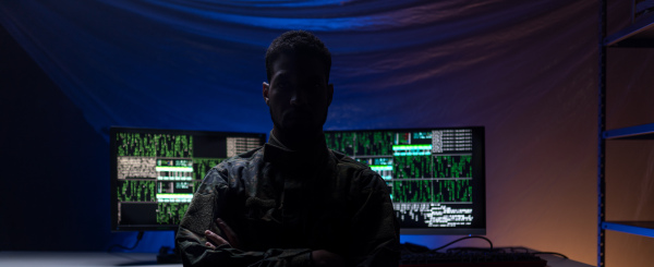 An anonymous hacker in military unifrorm on dark web, cyberwar concept.