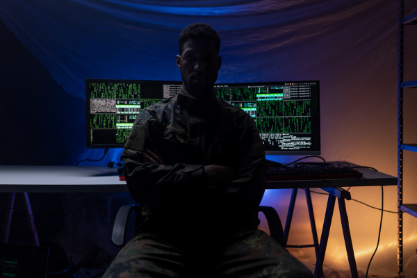 An anonymous hacker in military unifrorm on dark web, cyberwar concept.