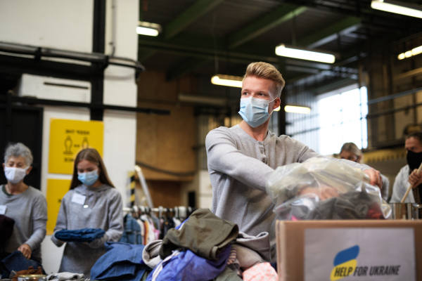 Volunteers sorting out donated clothes for the needs of the Ukrainian migrants, humanitarian aid concept.