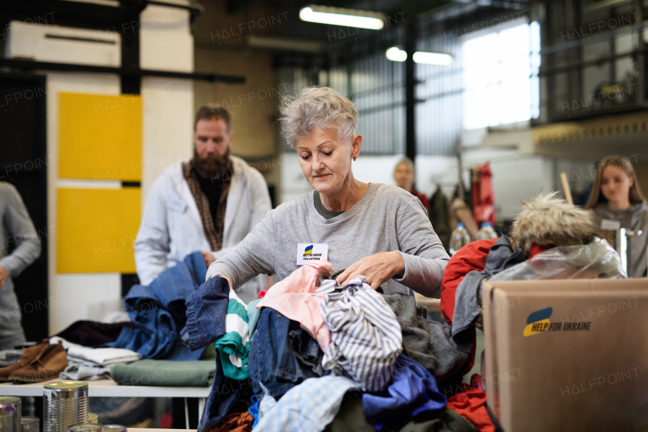 Volunteers sorting out donated clothes for the needs of the Ukrainian migrants, humanitarian aid concept.