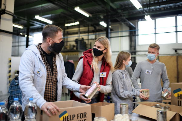 Volunteers sorting out donated food for the needs of the Ukrainian migrants, humanitarian aid concept.