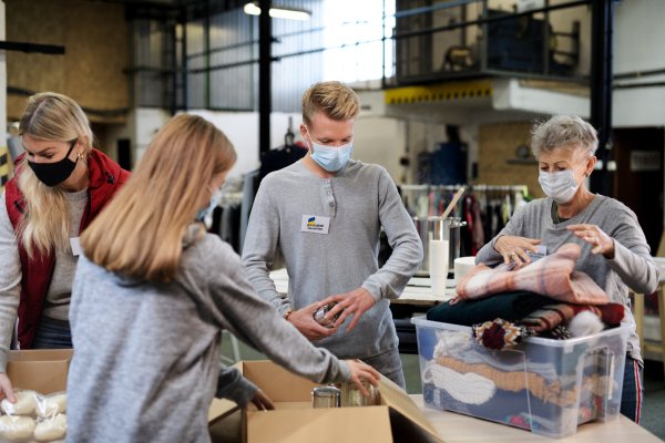 Volunteers sorting out donated food and clothes for the needs of the Ukrainian migrants, humanitarian aid concept.