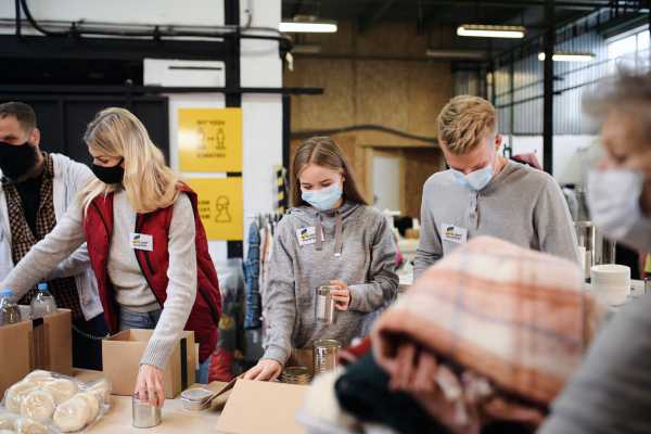 Volunteers sorting out donated food and clothes for the needs of the Ukrainian migrants, humanitarian aid concept.