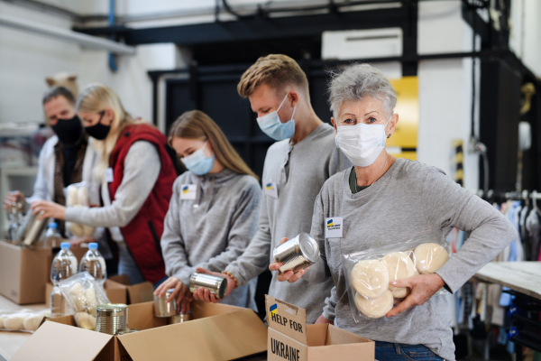 Volunteers sorting out donated food for the needs of the Ukrainian migrants, humanitarian aid concept.