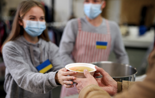 Volunteers serving hot soup for the Ukrainian migrants in refugee centre, Russian conflict concept.