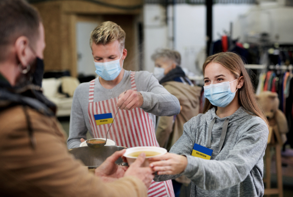 Volunteers serving hot soup for the Ukrainian migrants in refugee centre, Russian conflict concept.