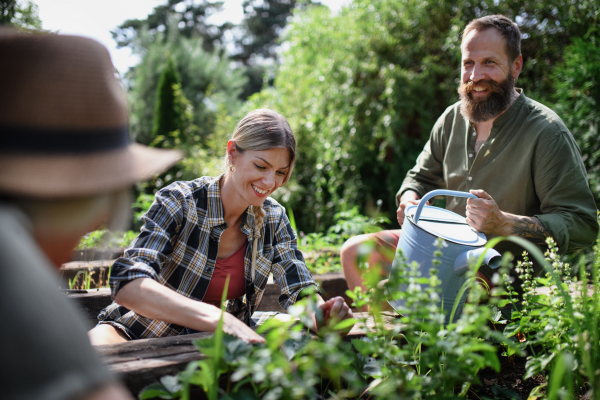 Happy young and old farmers working with garden tools outdoors at a community farm.