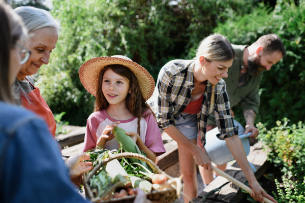 A happy farmers family working with garden tools outdoors at community farm.