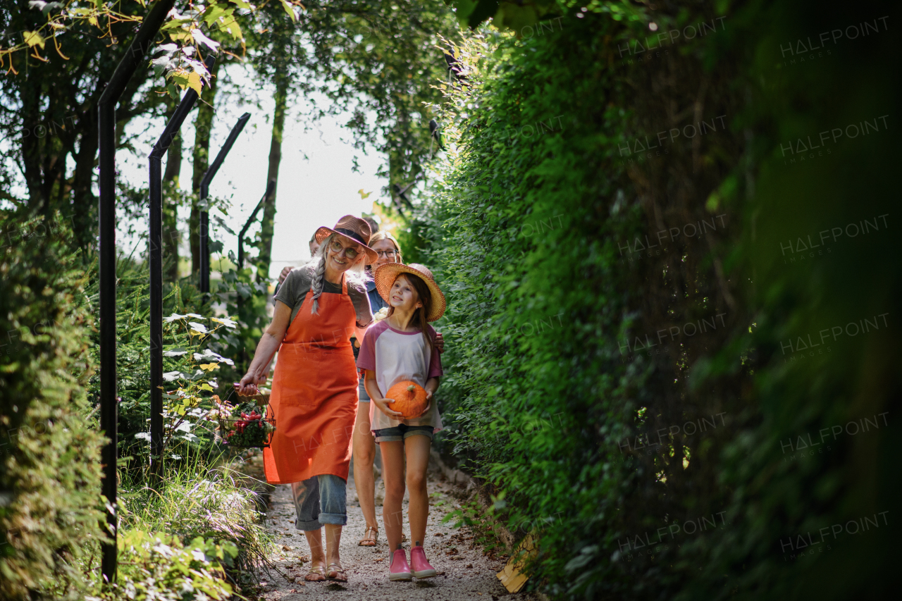 A happy little farmer girl with mother and grandmother looking at camera outdoors at garden