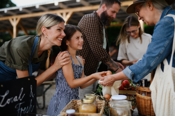 A happy woman buying organic eggs outdoors at local family farmers market.