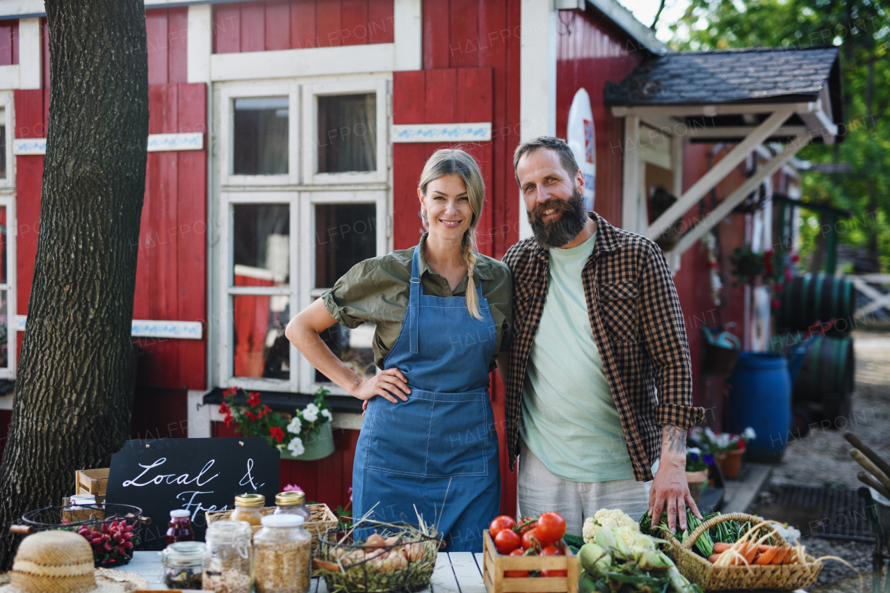 Mature couple farmers selling homegrown products at a community farmers market, looking at camera.