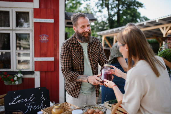 Woman buying organic juice outdoors at local farmers market.