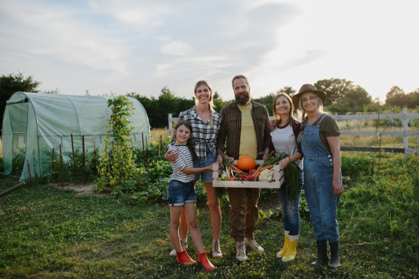 Happy young and old farmers or gardeners working outdoors at a community farm.