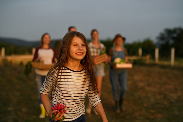 A happy farmer family holding their harvest outdoors in garden.