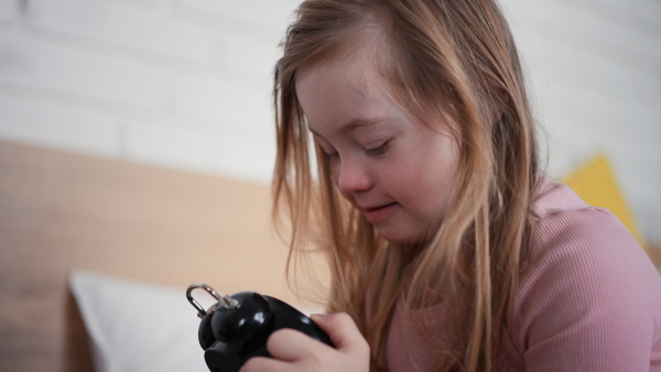 A little girl with Down syndrome playing with alarm clock at home.