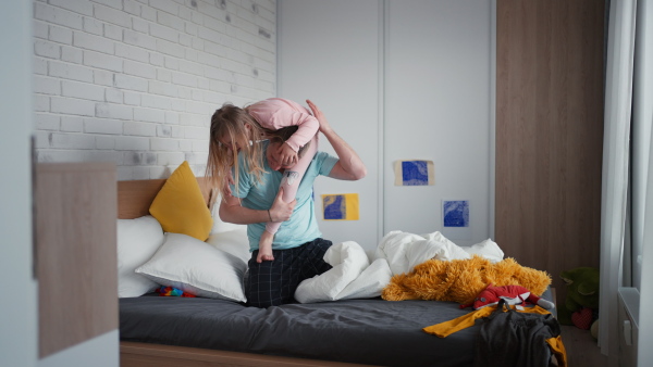 A father holding his little daughter with Down syndrome on shoulders at home.