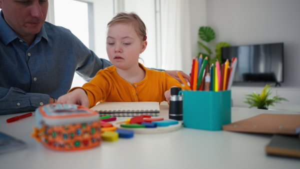 A father with his little daughter with Down syndrome learning at home.