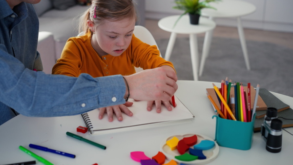 A father with his little daughter with Down syndrome drawing at home.