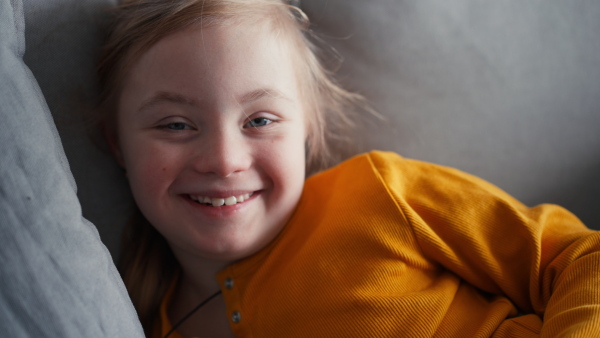 A little girl with Down syndrome resting and lying on bed at home.