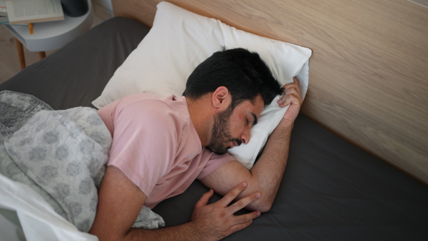 Young man sleeping in a bedroom, high angle view.