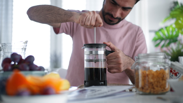 Close-up of young man doing coffee in a french press.