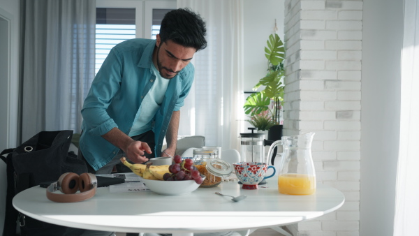 Young man hurrying up to work, taking a breakfast.