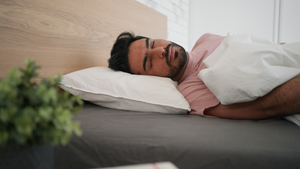 Young man sleeping in a bedroom, high angle view.