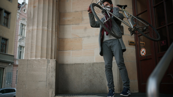 Young man with ffp2 respirator taking bicycle down the staircase.