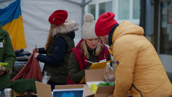 The volunteers distributing food and drink to refugees on the Ukrainian border, humanitarian aid concept.