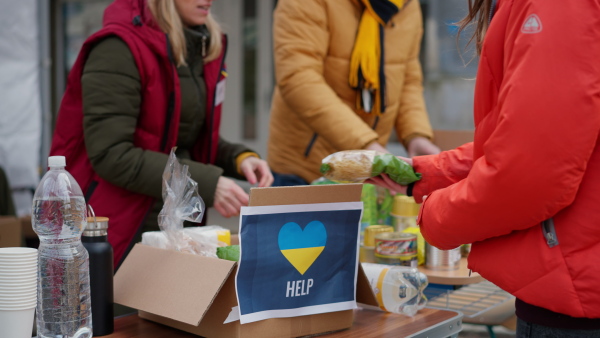 The volunteers distributing food and drink to refugees on the Ukrainian border, humanitarian aid concept.