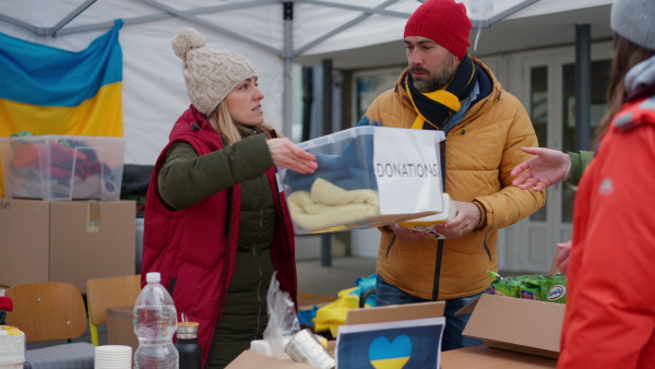 The volunteers distributing food and drink to refugees on the Ukrainian border, humanitarian aid concept.